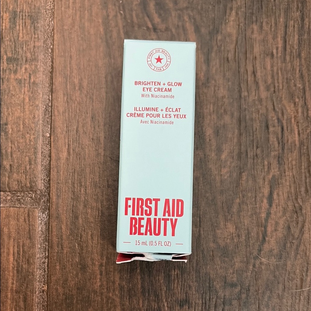 First Aid Beauty Brighten + Glow Eye Cream — White with Red Text